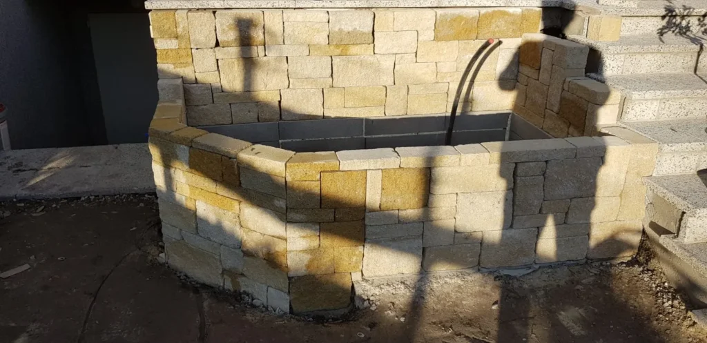Natursteinbecken im Rohbau mit Leitungen – Vorbereitung für Brunnen, Wasserlauf oder Zierelement