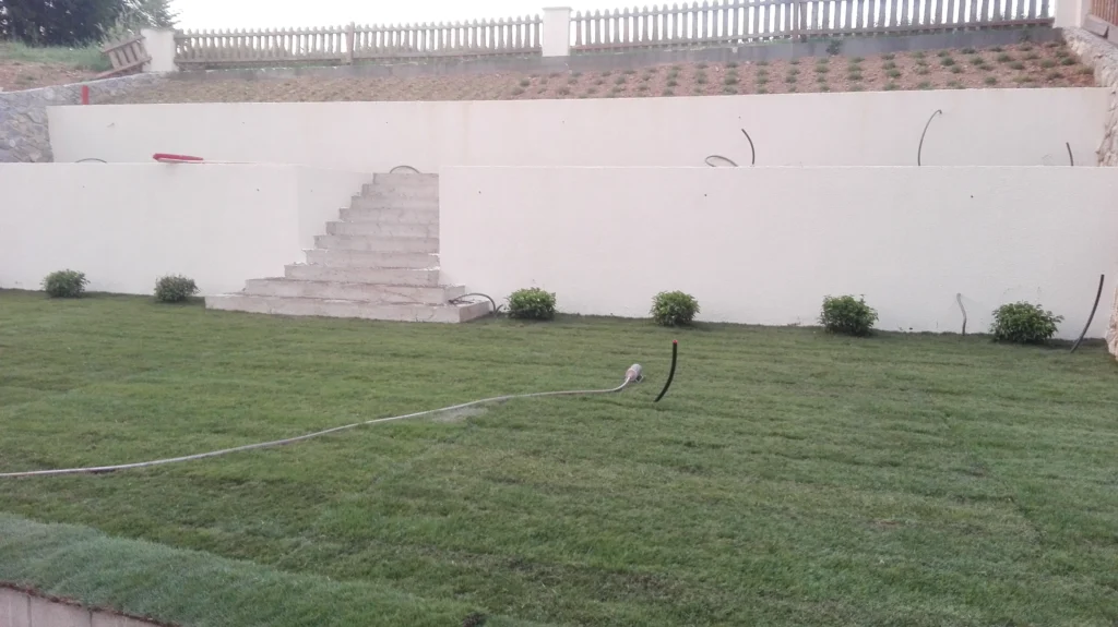 Verlegter Rollrasen mit vorbereiteten Leitungen für automatisches Bewässerungssystem im Garten